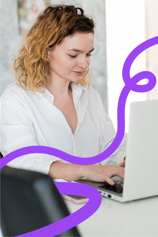 Fiatal nő fehér ingben egy laptop előtt dolgozik, miközben koncentráltan gépel. A kép dizájneleme egy lila, hullámos vonal, amely dinamikus vizuális hatást kelt.